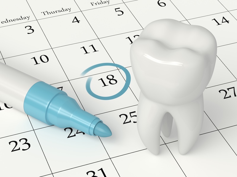 Dental appointment concept: calendar and tooth with appointment date circled in blue marker.