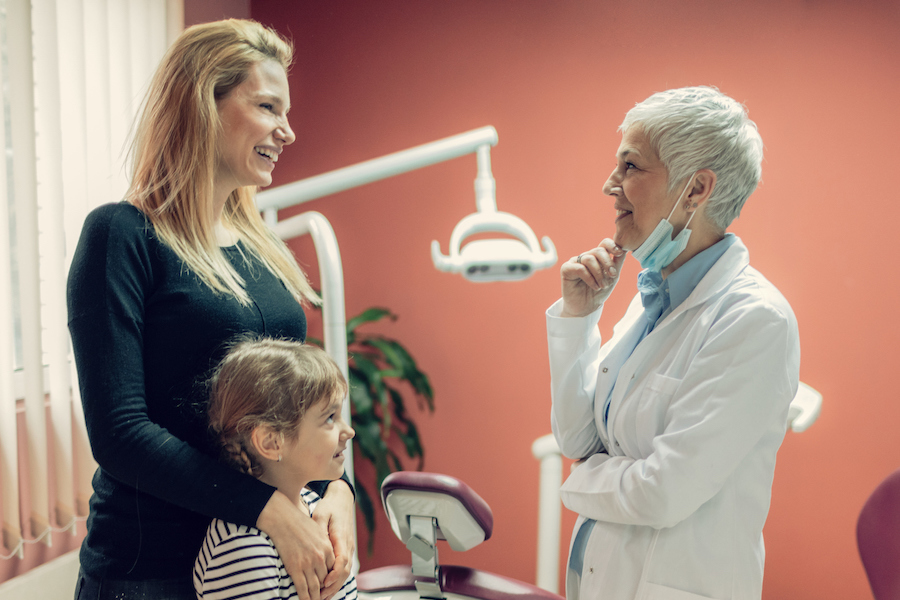 mother and daughter at dental office with dentist