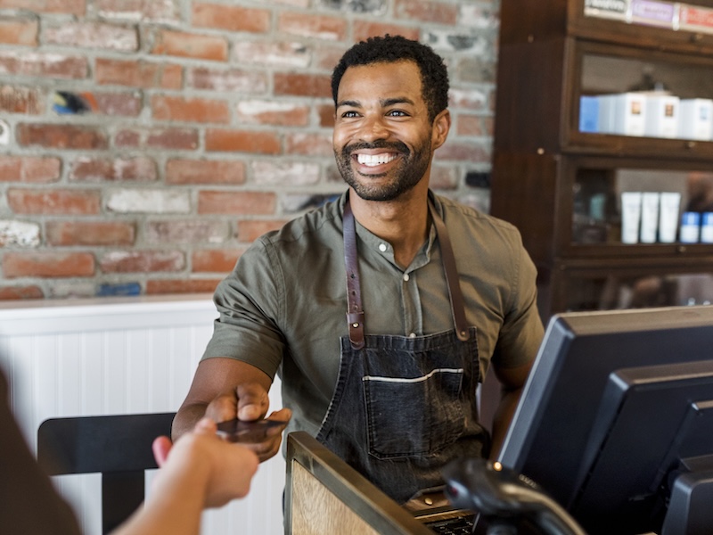 Male salon owner taking payment from a customer