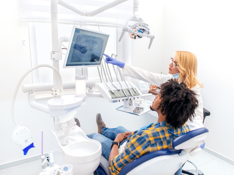 Dentist with patient looking at screen with oral images