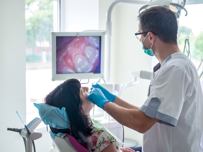 Dentist examining patient teeth with intraoral camera